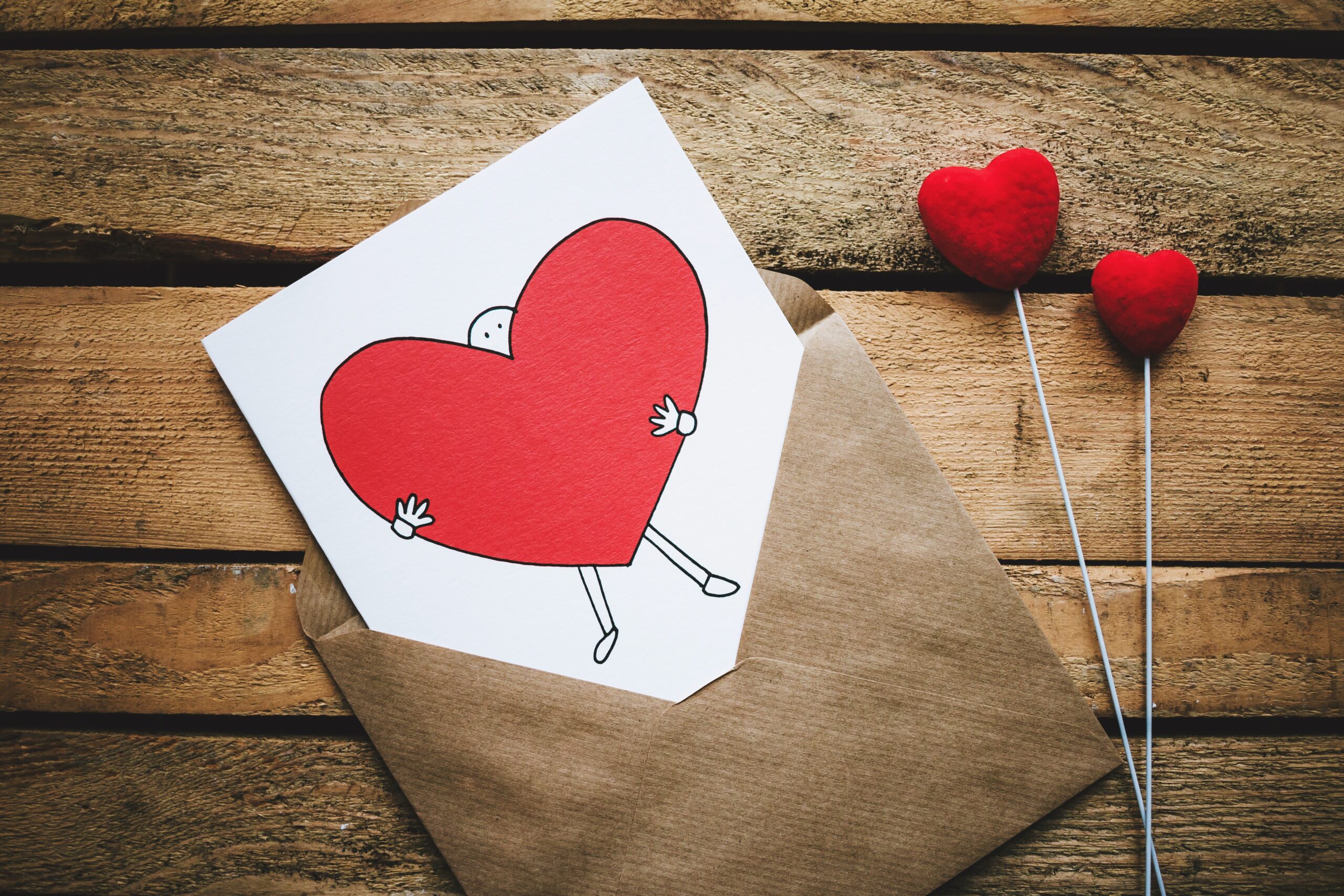 Photo of White, Black, and Red Person Carrying Heart Illustration in Brown Envelope